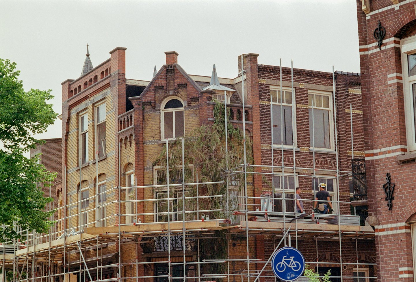 Operai edili su un ponteggio che ristrutturano un edificio storico in mattoni.
